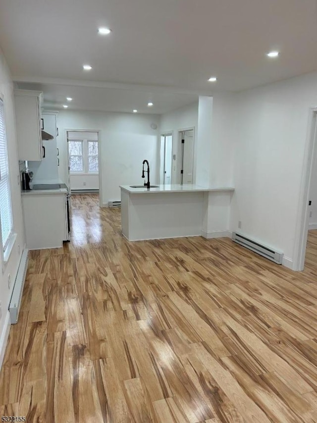 kitchen featuring a baseboard heating unit, a sink, white cabinetry, baseboard heating, and light wood finished floors