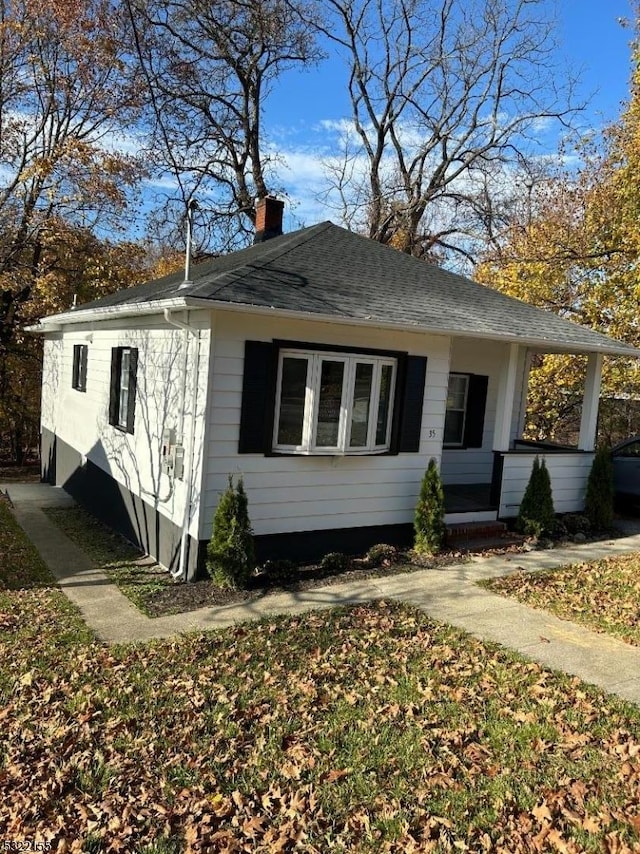 view of front of home with a shingled roof and a chimney