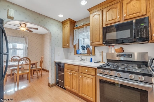 kitchen with sink, black appliances, light wood-type flooring, and ceiling fan