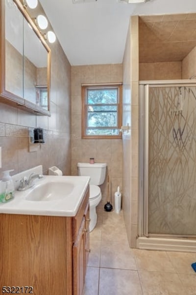 bathroom with vanity, toilet, tile patterned floors, and tile walls