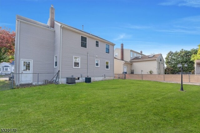 rear view of house with a lawn and central AC unit