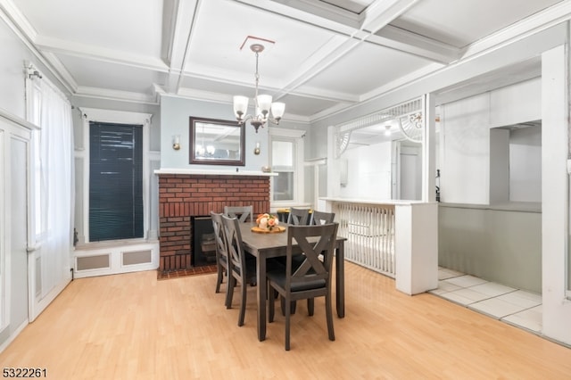 dining space featuring a healthy amount of sunlight, a brick fireplace, light hardwood / wood-style floors, coffered ceiling, and beamed ceiling