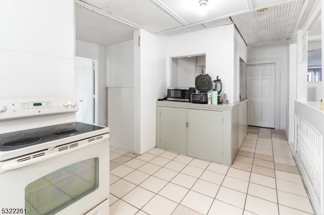 kitchen with light tile patterned floors, electric range, and white cabinets