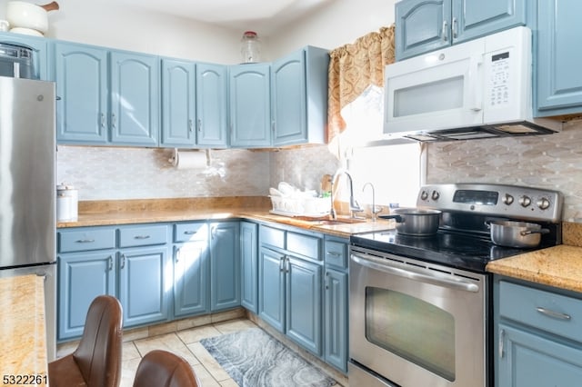 kitchen featuring blue cabinetry, appliances with stainless steel finishes, and backsplash