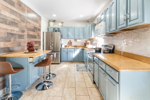 kitchen with a breakfast bar, tasteful backsplash, stainless steel appliances, and blue cabinets