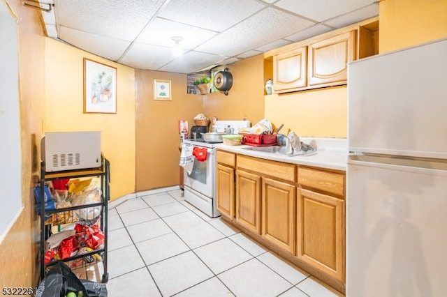 kitchen with sink, a drop ceiling, white appliances, and light tile patterned floors