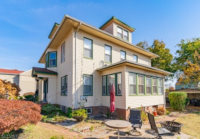 rear view of property with a patio area and a fire pit