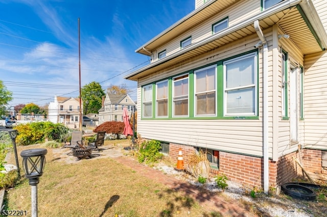 view of property exterior featuring an outdoor fire pit and a lawn