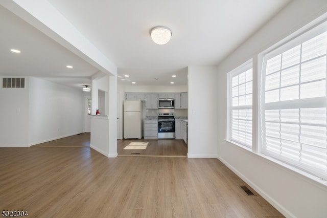 interior space featuring gray cabinetry, white refrigerator, stove, and light hardwood / wood-style flooring