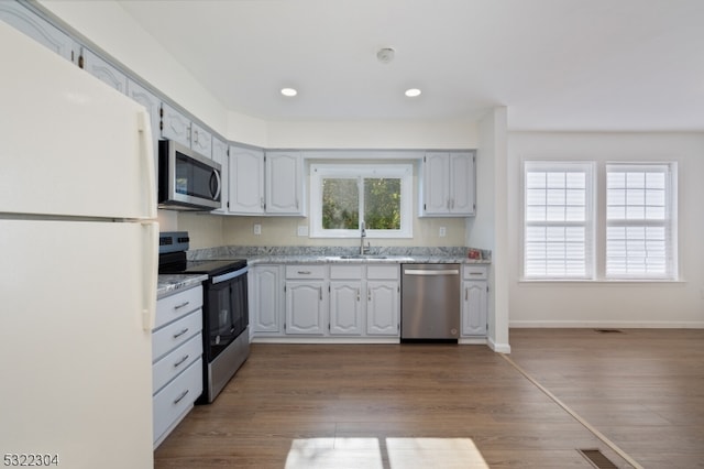 kitchen featuring light stone counters, sink, wood-type flooring, and stainless steel appliances