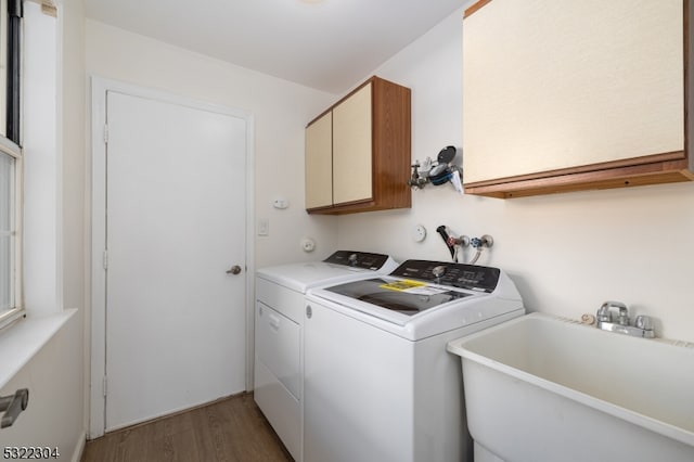 laundry area featuring cabinets, separate washer and dryer, hardwood / wood-style flooring, and sink