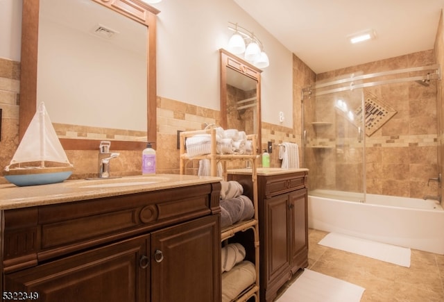 bathroom with vanity, tiled shower / bath combo, tile patterned floors, and tile walls