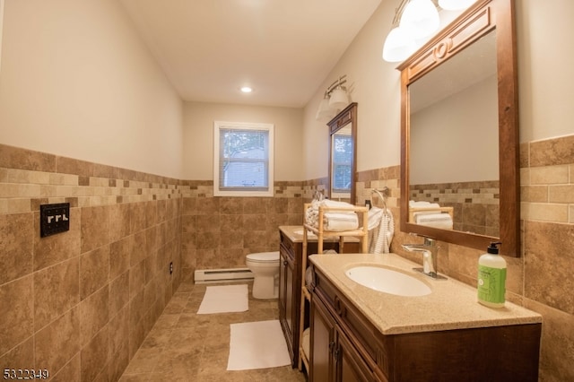 bathroom featuring baseboard heating, vanity, toilet, and tile walls