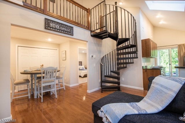 living room featuring wood-type flooring, high vaulted ceiling, and a skylight