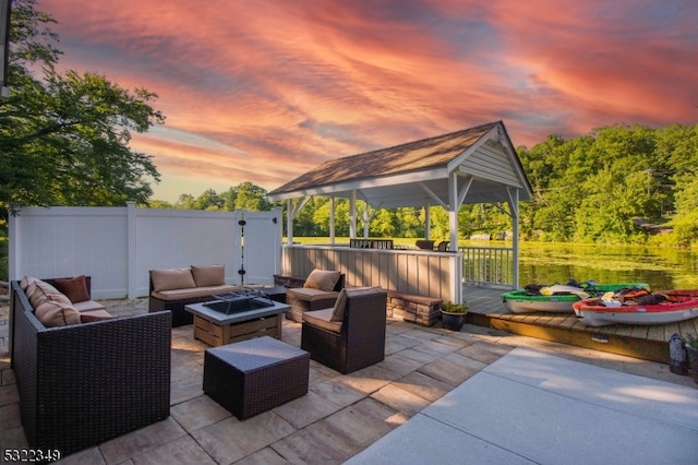 patio terrace at dusk featuring a gazebo, a deck, and an outdoor living space with a fire pit