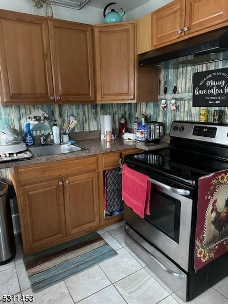 kitchen featuring sink, stainless steel electric range oven, backsplash, and light tile patterned floors