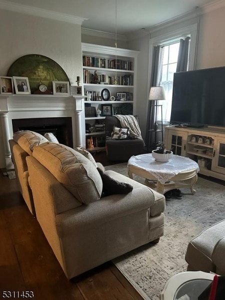 living room with dark hardwood / wood-style flooring, built in features, and ornamental molding