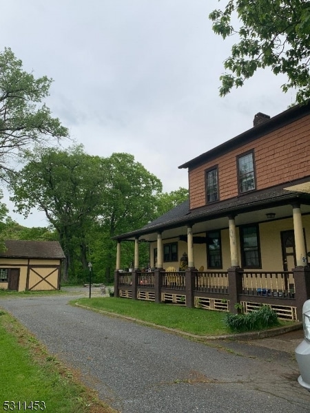 view of front of home with a porch and a shed