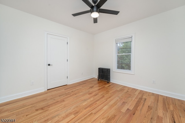 empty room with ceiling fan, radiator heating unit, and light hardwood / wood-style flooring