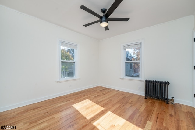 unfurnished room featuring radiator heating unit, ceiling fan, and light hardwood / wood-style flooring