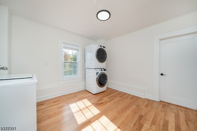 clothes washing area with stacked washing maching and dryer, light hardwood / wood-style flooring, and sink