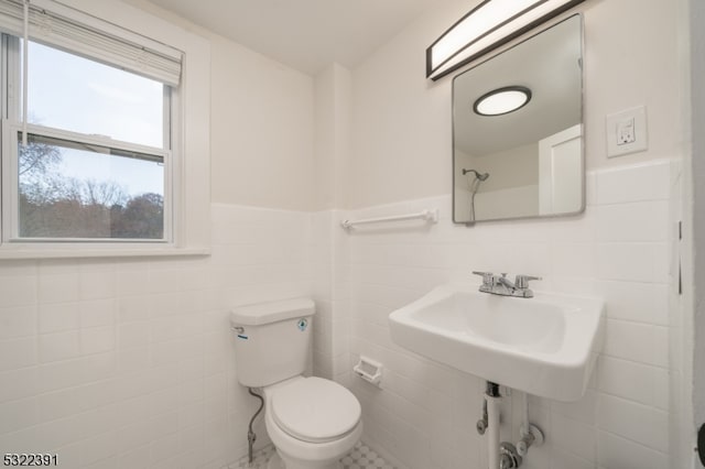 bathroom featuring toilet, tile walls, and sink