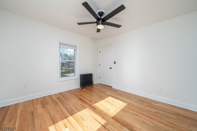 spare room featuring radiator heating unit, ceiling fan, and light hardwood / wood-style flooring