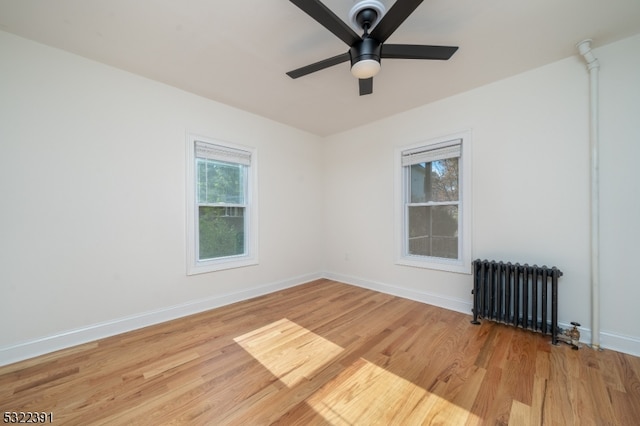 unfurnished room featuring light hardwood / wood-style floors, plenty of natural light, and radiator heating unit