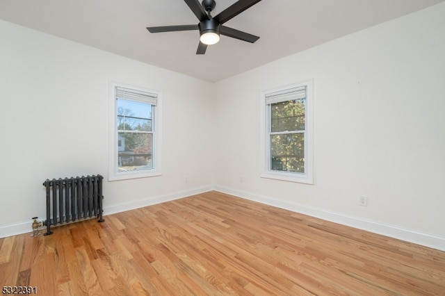 spare room with radiator, ceiling fan, and light wood-type flooring