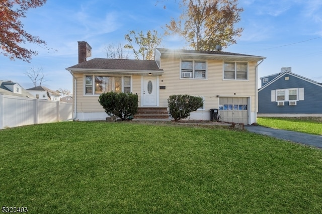 tri-level home featuring a garage and a front lawn