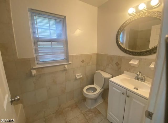 bathroom with tile patterned floors, vanity, toilet, and tile walls