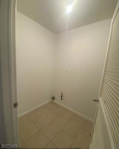 clothes washing area with light tile patterned floors