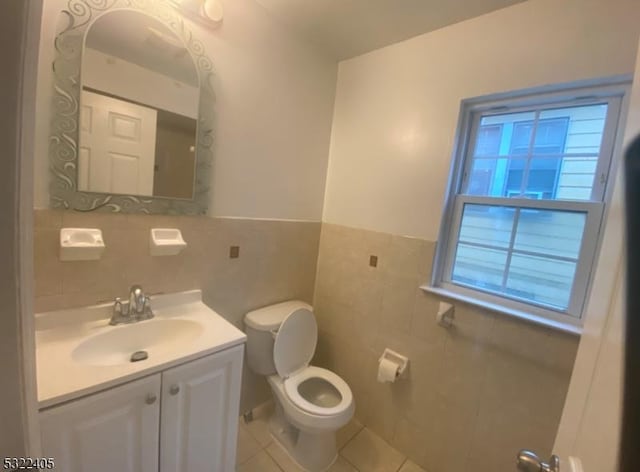 bathroom featuring tile patterned flooring, vanity, toilet, and tile walls