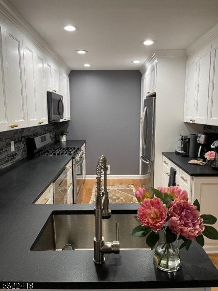 kitchen featuring decorative backsplash, white cabinetry, sink, and appliances with stainless steel finishes