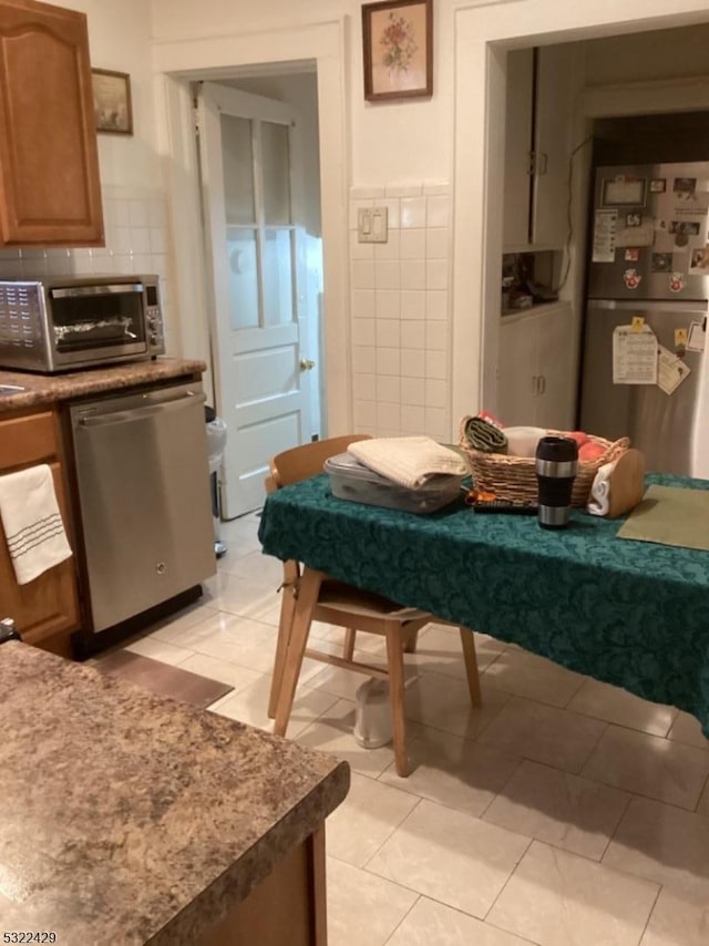 kitchen featuring light tile patterned flooring, tile walls, and appliances with stainless steel finishes