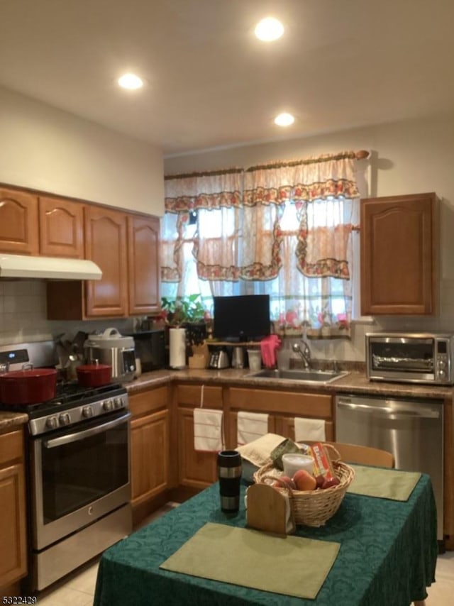 kitchen featuring backsplash, sink, light tile patterned flooring, and appliances with stainless steel finishes