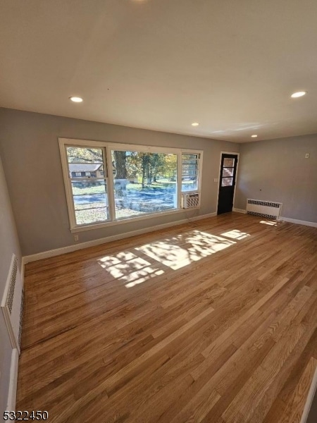 unfurnished living room with radiator and wood-type flooring