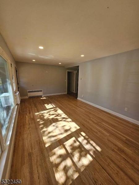 unfurnished living room featuring radiator heating unit and hardwood / wood-style floors