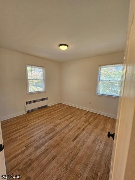 unfurnished room with radiator heating unit and hardwood / wood-style flooring