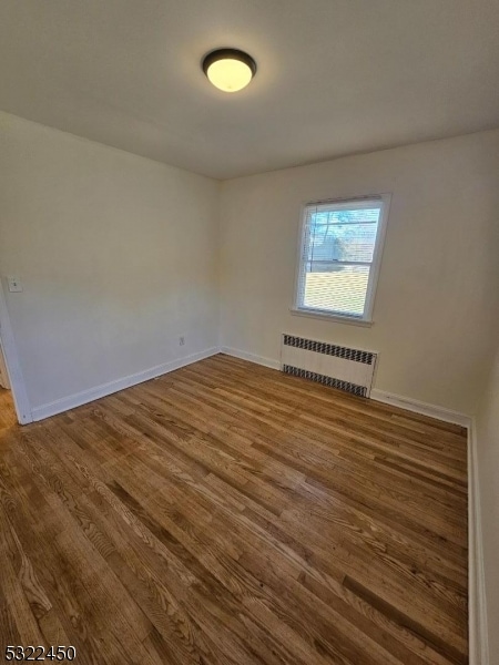 empty room with hardwood / wood-style flooring and radiator