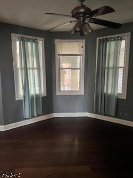 empty room with ceiling fan, plenty of natural light, and hardwood / wood-style floors