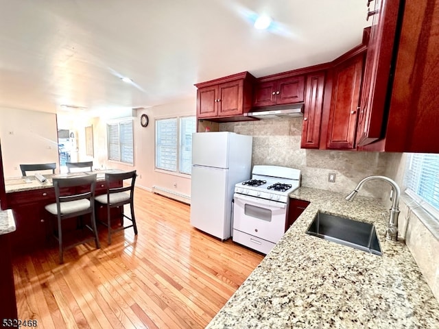 kitchen with white appliances, baseboard heating, sink, and light hardwood / wood-style flooring