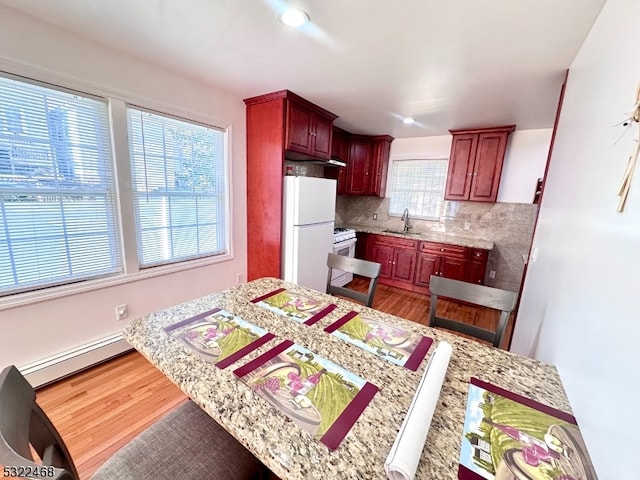 kitchen with plenty of natural light, tasteful backsplash, hardwood / wood-style flooring, and white appliances