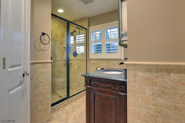 bathroom with vanity, tile walls, and a shower with door