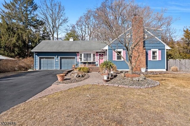 view of front of house with aphalt driveway, fence, a chimney, and an attached garage