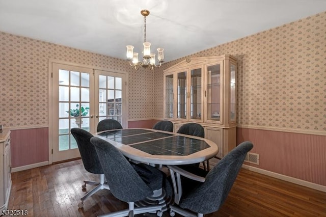 dining space with a chandelier, visible vents, wainscoting, wood-type flooring, and wallpapered walls