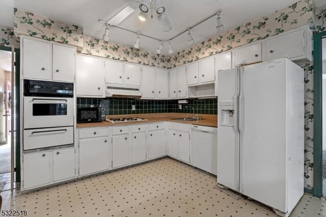 kitchen with white appliances, a warming drawer, under cabinet range hood, and light floors