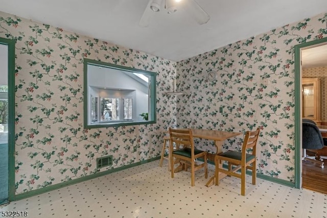 unfurnished dining area with baseboards, ceiling fan, visible vents, and wallpapered walls