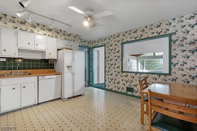 kitchen with light floors, white cabinets, a sink, white appliances, and wallpapered walls