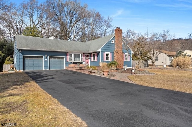 single story home with aphalt driveway, a chimney, and an attached garage